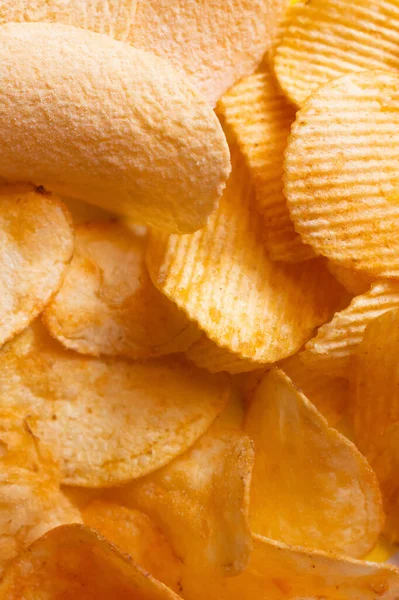 Куча разных вкусных и соленых картофельных чипсов, вид сверху — стоковое фото