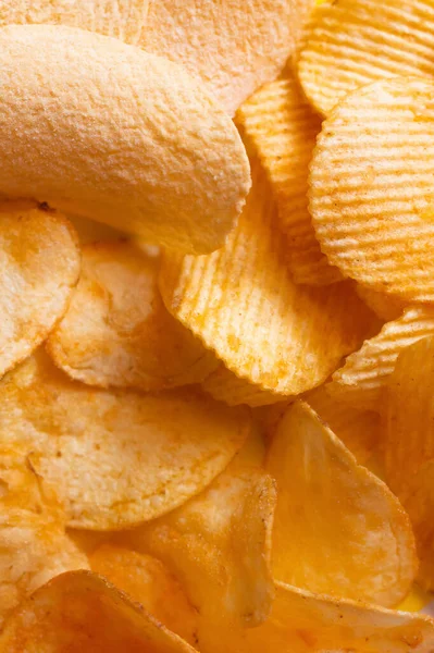 Bunch of different delicious and salty potato chips, top view — Stock Photo