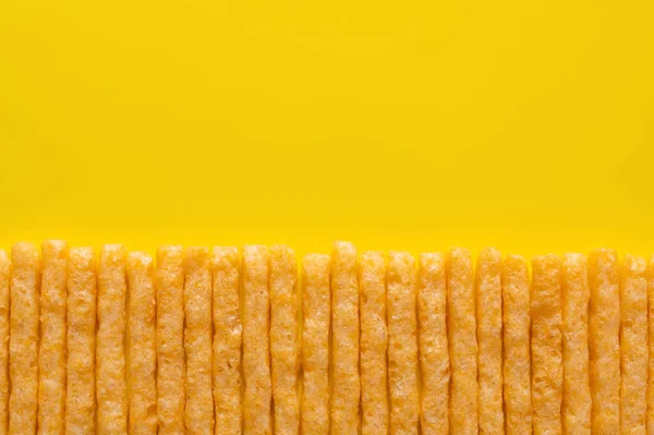 Плоская укладка вкусной и соленой картошки фри на желтом — стоковое фото
