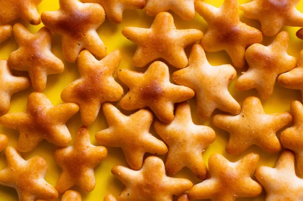 Close up view of tasty cookies in shape of stars on yellow — Stock Photo