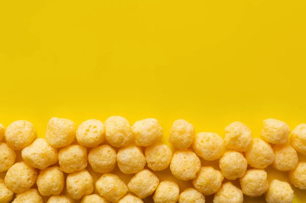 Flat lay of puffed and tasty cheese pops on yellow — Stockfoto