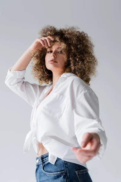 Low angle view of young woman in blouse looking at camera isolated on white — Stock Photo