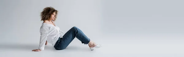 Modelo rizado en blusa sentado sobre fondo blanco, bandera - foto de stock