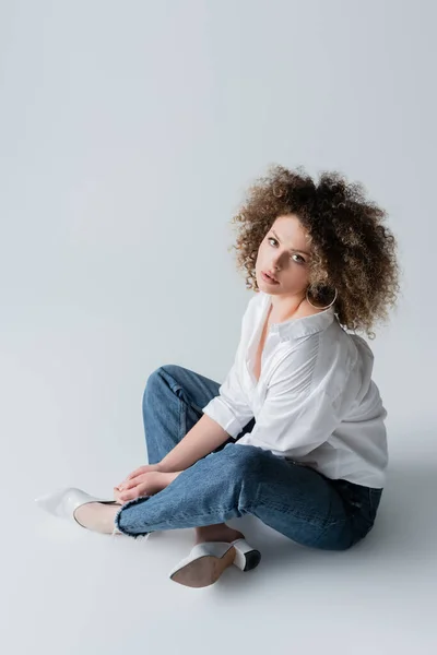 Высокий угол зрения стильной молодой женщины, сидящей на белом фоне — стоковое фото