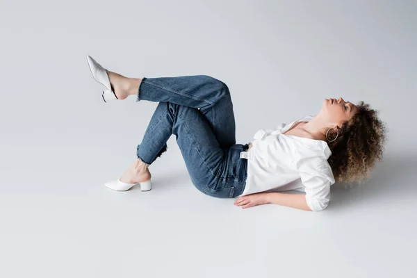 Elegante donna in jeans e camicetta sdraiata su sfondo bianco — Foto stock