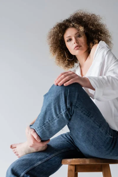 Low angle view of barefoot model sitting on chair isolated on white — Stock Photo