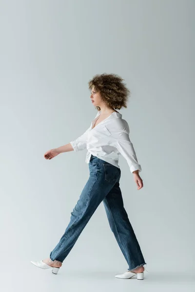 Side view of stylish woman walking on white background — Stock Photo