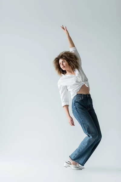 Jolie femme en jean et chemisier posant sur fond blanc — Photo de stock