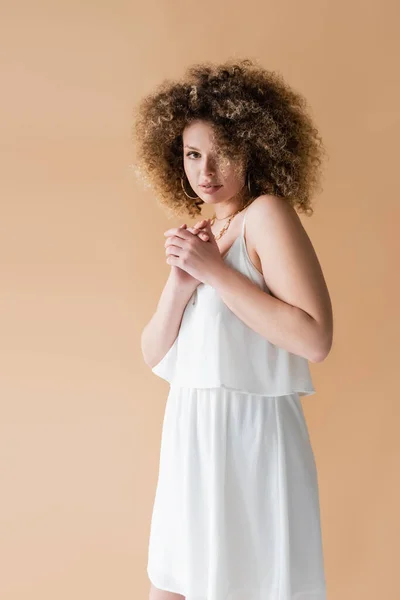 Portrait of curly model in white clothes isolated on beige — Stock Photo