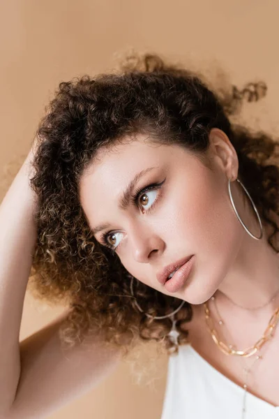 Portrait of young woman touching hair isolated on beige — Stock Photo