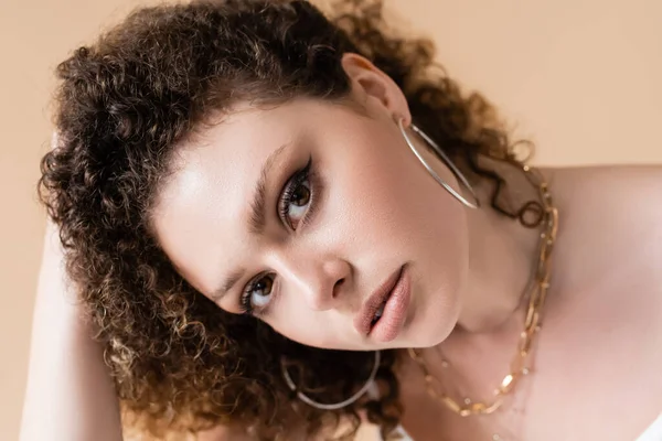 Portrait of young curly model looking at camera isolated on beige — Stock Photo