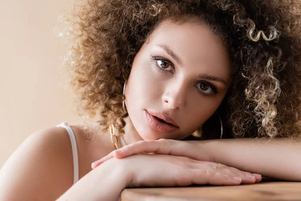 Ritratto di donna riccia che guarda la macchina fotografica isolata sul beige — Foto stock