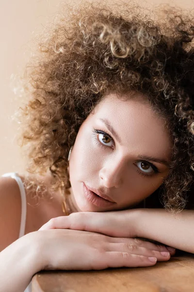 Portrait of young curly woman looking at camera isolated on beige — Stock Photo