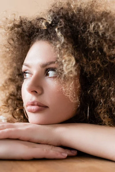 Jeune modèle bouclé regardant loin isolé sur beige — Photo de stock