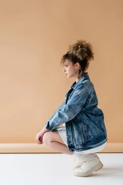 Side view of trendy model in boots posing on beige background — Stock Photo