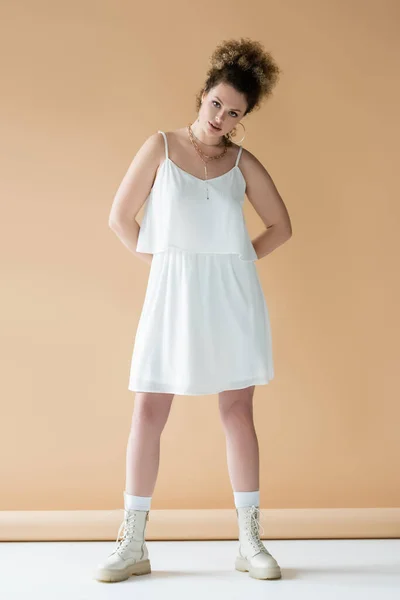 Full length of stylish curly model posing on beige background — Stock Photo