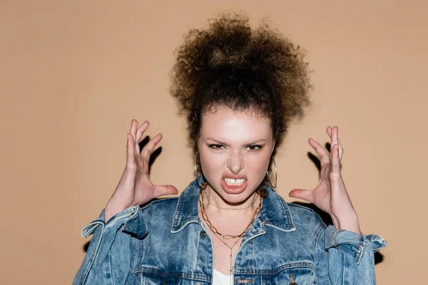 Modèle en colère en jean veste regardant la caméra sur fond beige — Photo de stock