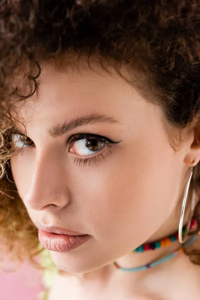 Close up view of curly woman looking at camera isolated on pink — Stock Photo