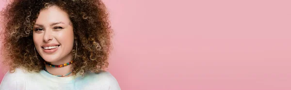 Young woman winking and smiling at camera isolated on pink, banner — Stock Photo