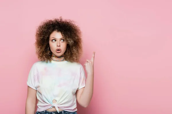 Shocked woman pointing with finger at pink background — Stock Photo