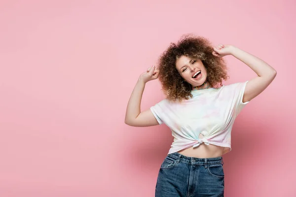 Positivo riccio donna toccare i capelli su sfondo rosa — Foto stock