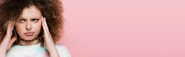 Pensive curly woman touching head isolated on pink, banner — Stock Photo