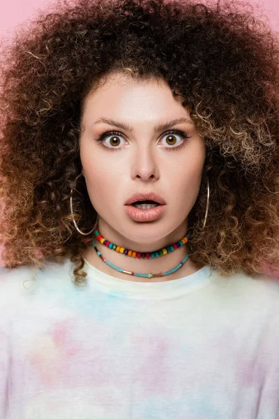 Shocked curly woman looking at camera isolated on pink — Stock Photo