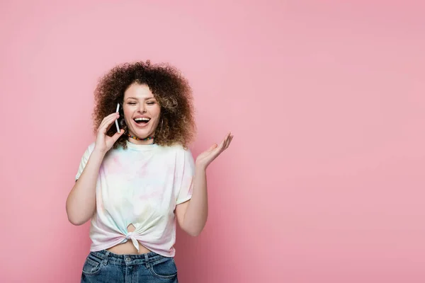 Joven alegre hablando por teléfono celular aislado en rosa - foto de stock