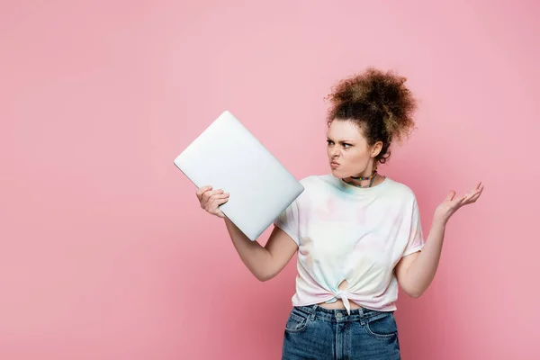 Freelancer irritado em t-shirt olhando para laptop isolado em rosa — Fotografia de Stock