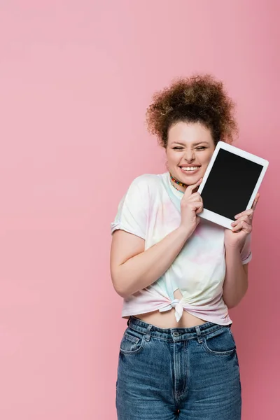 Mujer feliz en ropa casual sosteniendo tableta digital aislada en rosa - foto de stock