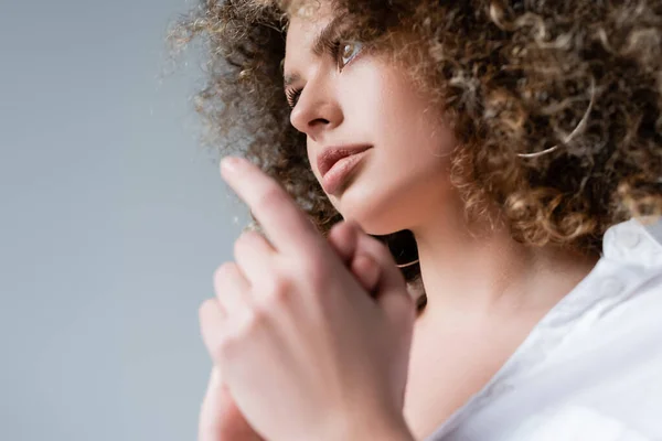 Vista de ángulo bajo de una mujer bastante rizada mirando hacia otro lado aislada en gris - foto de stock