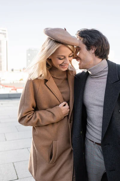 Homme en manteau d'automne riant près de femme élégante en béret à l'extérieur — Photo de stock