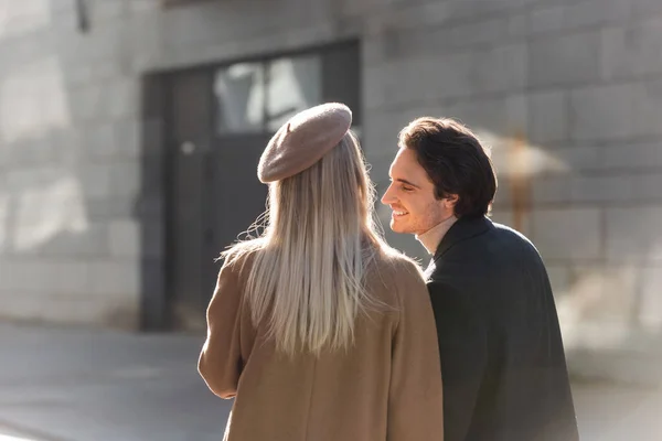 Donna bionda in berretto vicino all'uomo giovane e felice sulla strada della città — Foto stock