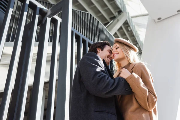 Vue à angle bas du couple romantique avec les yeux fermés embrassant près de la clôture en ville — Photo de stock