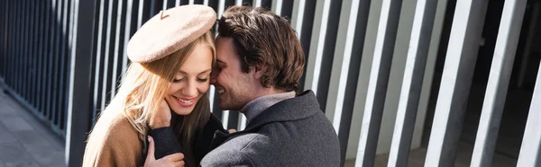 Homme souriant touchant le visage de la jeune femme en béret près de la clôture, bannière — Photo de stock