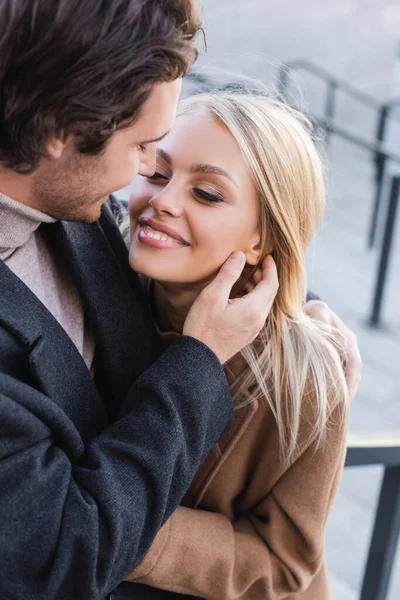 Jeune femme blonde souriant près de l'homme en manteau à l'extérieur — Photo de stock