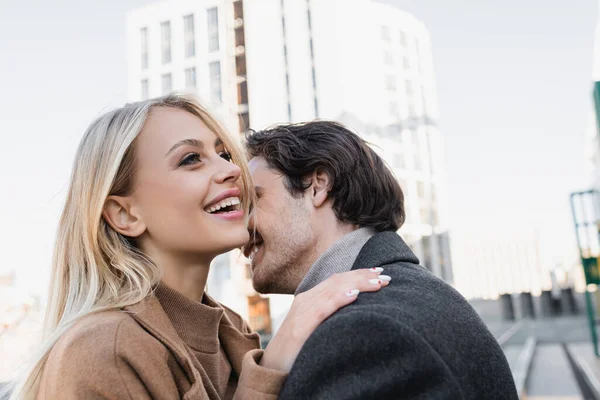 Cheerful blonde woman touching shoulder of young man outdoors — Stock Photo