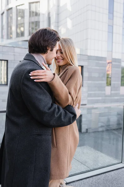 Jeune couple romantique en manteaux tendance embrassant sur la rue de la ville — Photo de stock