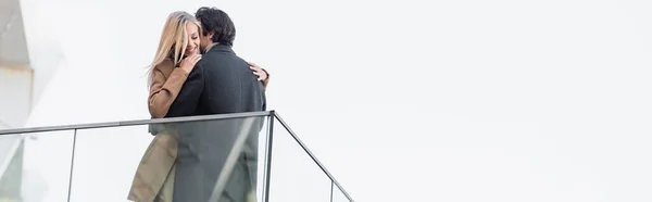 Vista de ángulo bajo de la pareja joven en ropa de otoño abrazando al aire libre, bandera — Stock Photo