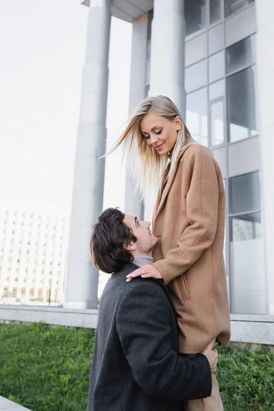 Giovane uomo abbracciare fidanzata in piedi sopra di lui sulla strada della città — Foto stock