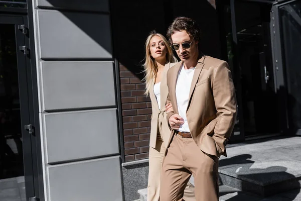 Trendy man with hand in pocket near blonde woman looking away on street — Stock Photo