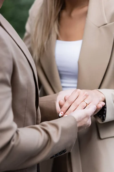 Vista recortada del hombre de la mano de la mujer con anillo de bodas en el dedo - foto de stock