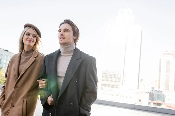 Femme heureuse en béret regardant jeune homme tout en marchant à l'extérieur — Photo de stock