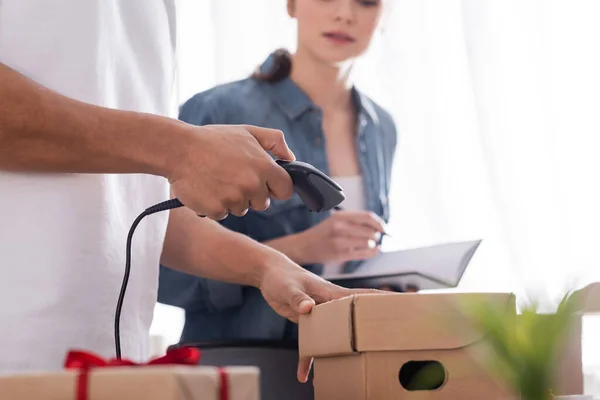 Vista recortada de la caja de cartón de escaneo de vendedor afroamericano cerca de colega en tienda web en línea - foto de stock