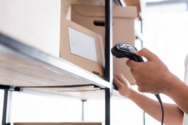 Ausgeschnittene Ansicht eines afrikanisch-amerikanischen Verkäufers scannt Versandetikett auf der Verpackung im Geschäft — Stockfoto