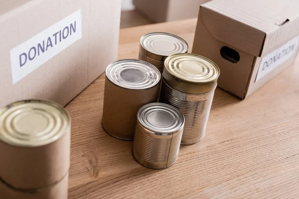 Canned food near boxes with donation lettering on table — Stock Photo