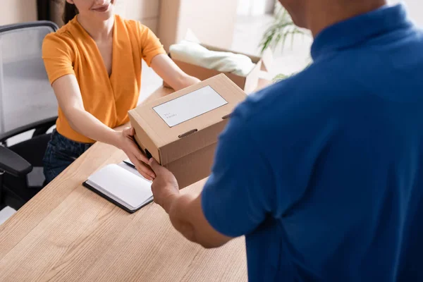 Cropped view of owner giving cardboard box to african american deliveryman in online web store — Stock Photo