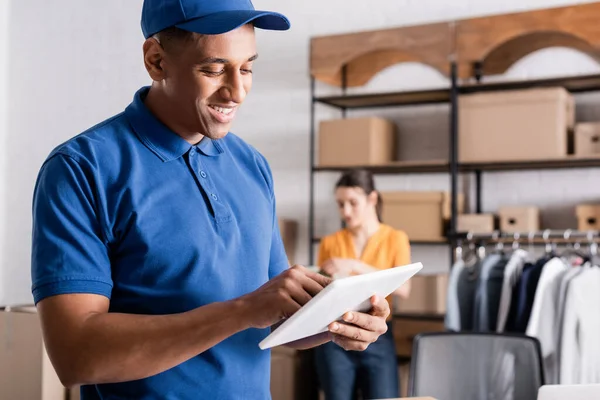 Lächelnder afrikanisch-amerikanischer Zusteller mit digitalem Tablet im Online-Webshop — Stockfoto