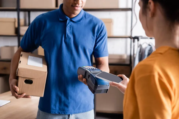 African american deliveryman holding box and payment terminal near proprietor in online web store — Stock Photo