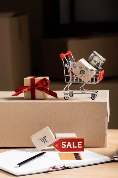 Carro de juguete con dinero, caja de regalo y tarjeta de crédito en el cuaderno en la mesa - foto de stock